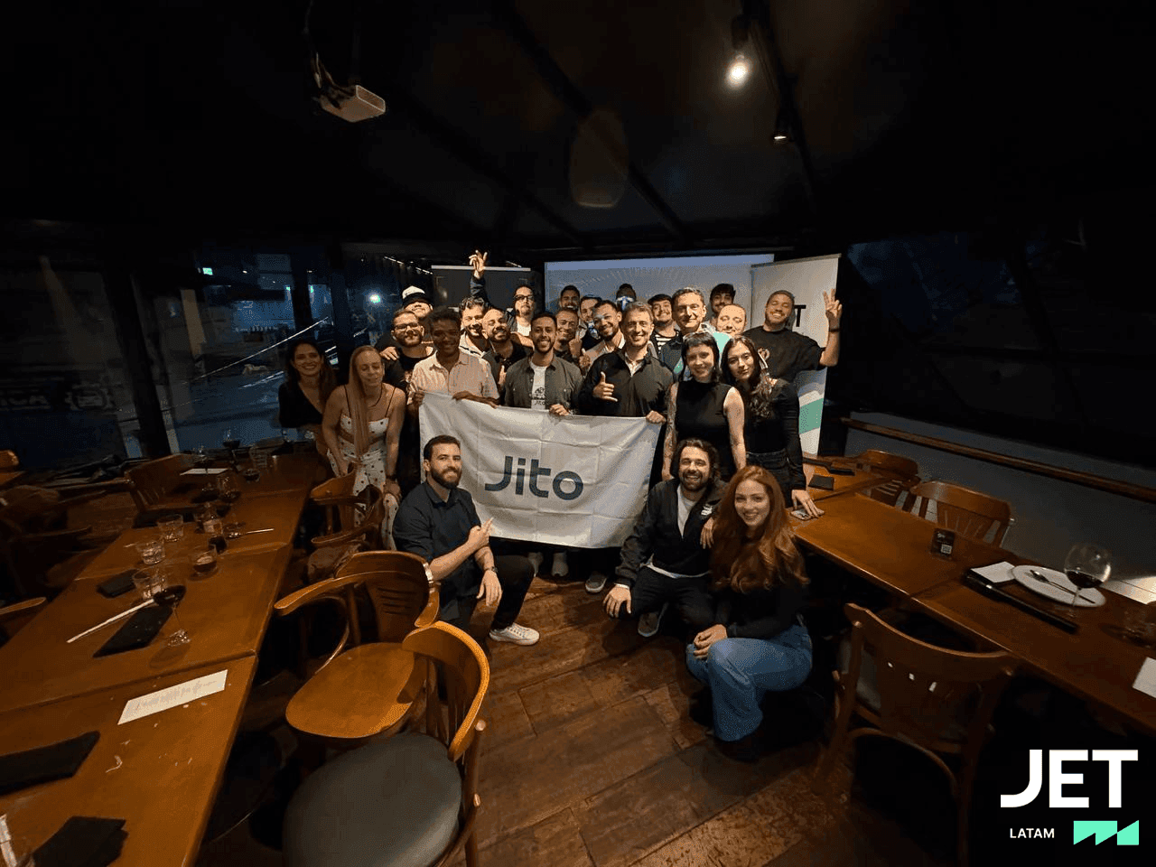 Convidados do JTX Private Dinner reunidos com a bandeira da Jito